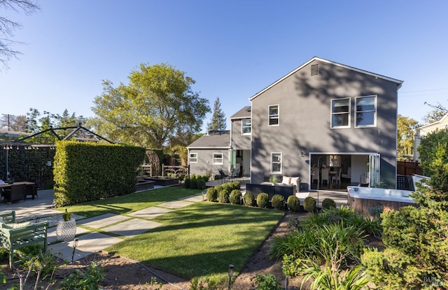rear view of house with stucco siding, fence, a yard, and a patio area