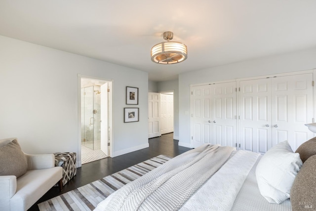 bedroom with dark wood-style floors, multiple closets, baseboards, and ensuite bath