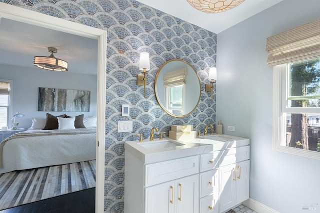 ensuite bathroom with wallpapered walls, a sink, connected bathroom, and a wealth of natural light
