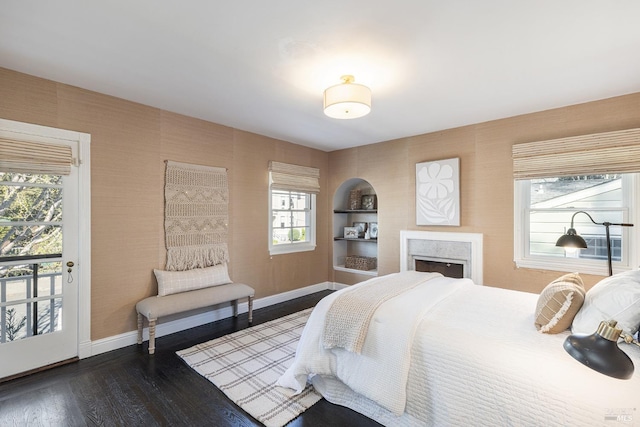 bedroom with wallpapered walls, baseboards, a fireplace, and dark wood finished floors