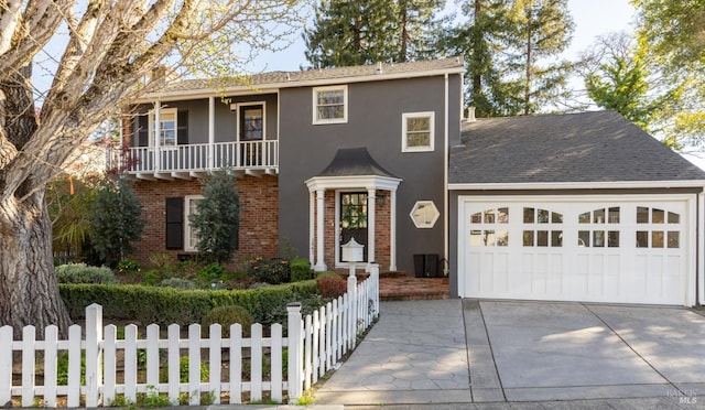 traditional home with a balcony, fence, a garage, concrete driveway, and brick siding