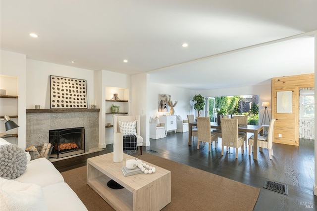 living area with recessed lighting, dark wood-style flooring, visible vents, and a tiled fireplace