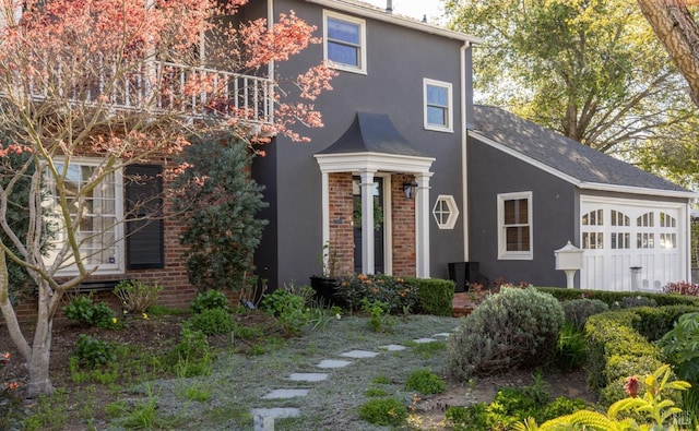 view of front of property featuring brick siding, a balcony, and stucco siding
