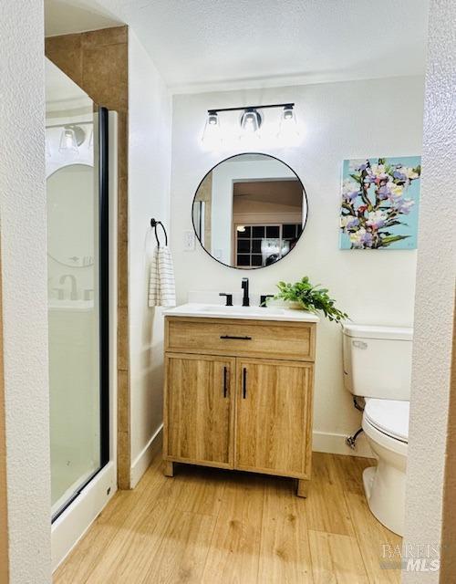 1242 Van Buren St, Fairfield, CA 94533 - bathroom featuring wood finished floors, toilet, vanity, baseboards, and a stall shower