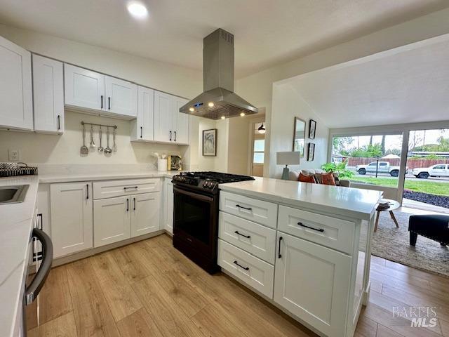 1242 Van Buren St, Fairfield, CA 94533 - kitchen featuring island range hood, range with gas stovetop, a peninsula, light countertops, and white cabinetry