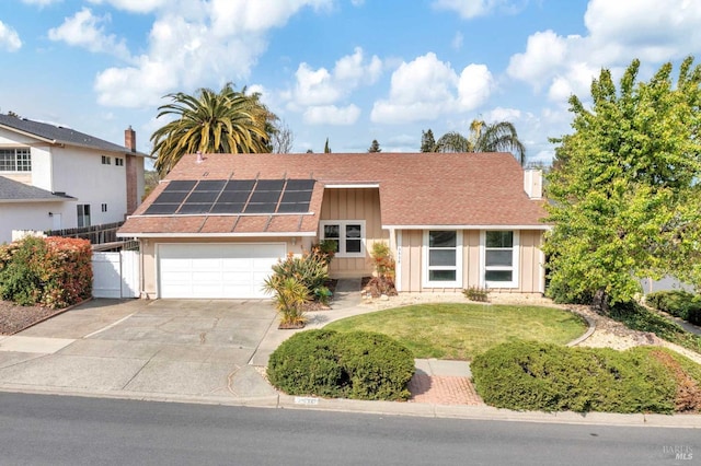 view of front of home with solar panels, an attached garage, board and batten siding, fence, and driveway