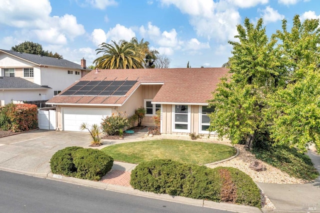 view of front facade with driveway, a front yard, solar panels, a garage, and fence
