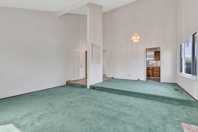 unfurnished living room with high vaulted ceiling, beamed ceiling, visible vents, carpet flooring, and a notable chandelier