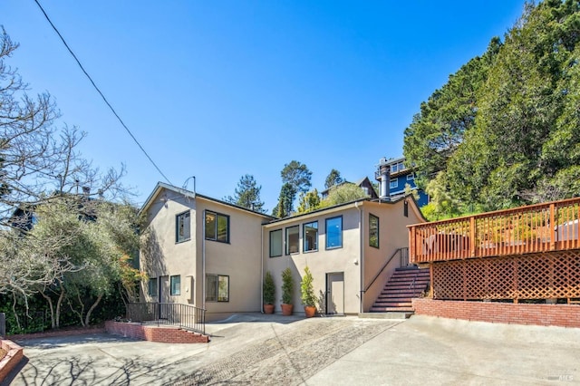 view of front of property featuring stucco siding, concrete driveway, and stairway