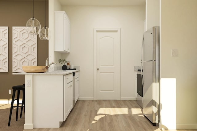 kitchen featuring white cabinets, a sink, light countertops, freestanding refrigerator, and light wood-type flooring