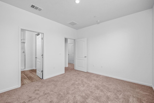 unfurnished bedroom with carpet floors, baseboards, and visible vents