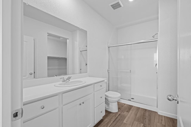 bathroom featuring a stall shower, toilet, wood finished floors, and visible vents