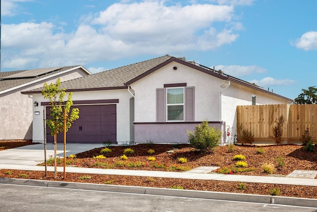 ranch-style home featuring a garage, fence, roof with shingles, stucco siding, and concrete driveway