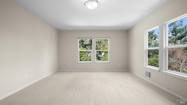 empty room featuring baseboards, light colored carpet, and visible vents