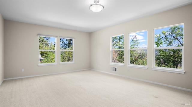 carpeted empty room featuring baseboards and visible vents