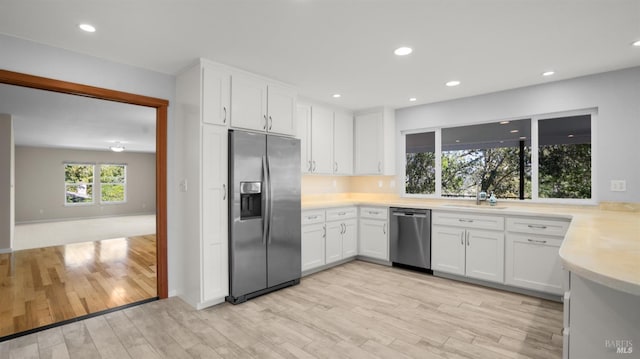 kitchen featuring white cabinetry, light countertops, stainless steel appliances, and light wood finished floors