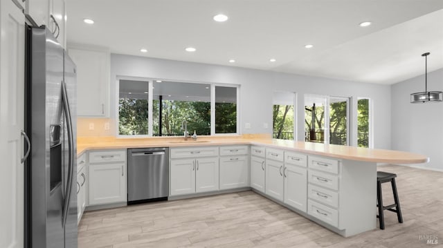 kitchen featuring light countertops, recessed lighting, appliances with stainless steel finishes, a sink, and a kitchen breakfast bar