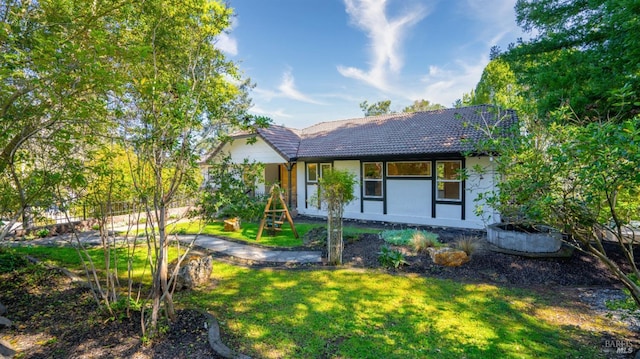 view of front of property featuring a front yard, a tiled roof, and stucco siding