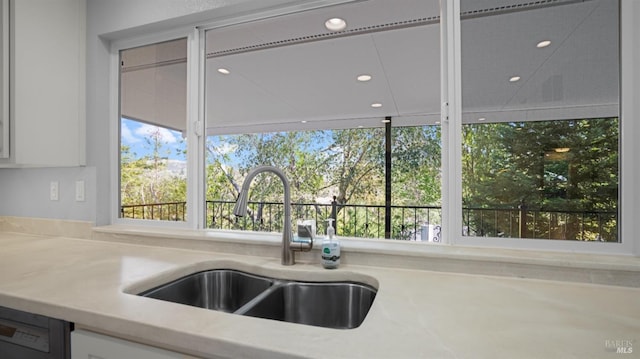 kitchen featuring light countertops, recessed lighting, white cabinetry, a sink, and dishwashing machine
