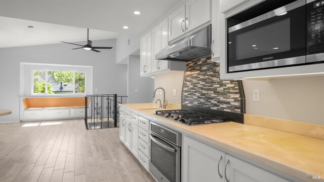 kitchen featuring white cabinets, stainless steel appliances, a ceiling fan, tasteful backsplash, and under cabinet range hood