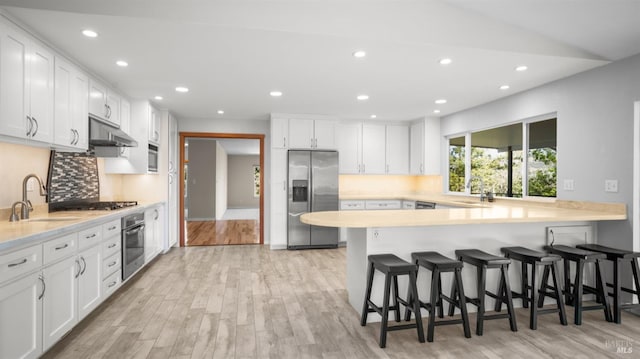 kitchen featuring light countertops, a sink, appliances with stainless steel finishes, and under cabinet range hood