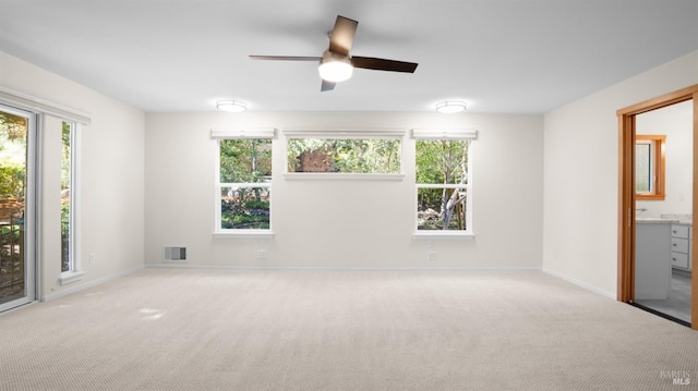 carpeted spare room with baseboards, visible vents, and a ceiling fan