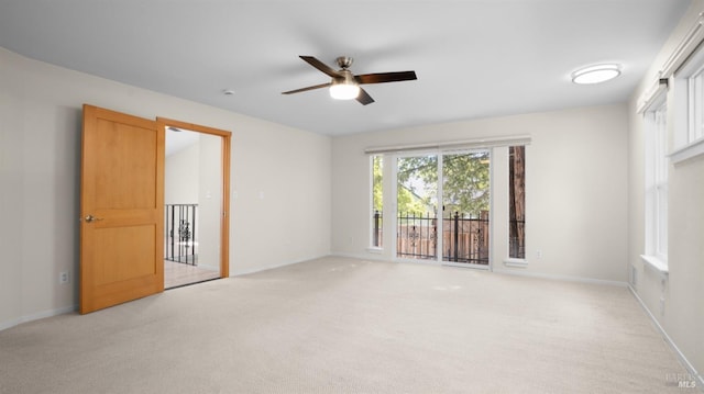 empty room featuring baseboards, a ceiling fan, and light colored carpet