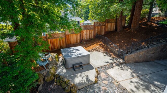 view of storm shelter featuring a jacuzzi, fence private yard, and a patio area