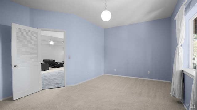 empty room with carpet flooring, baseboards, and lofted ceiling