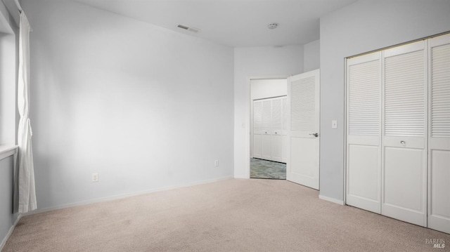 unfurnished bedroom with baseboards, visible vents, a closet, and carpet floors
