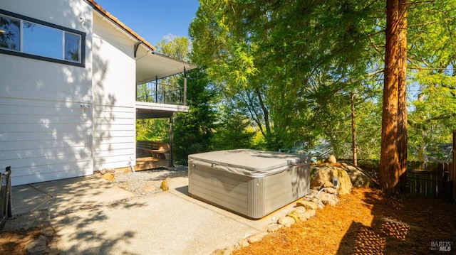 exterior space with a balcony, fence, and a hot tub