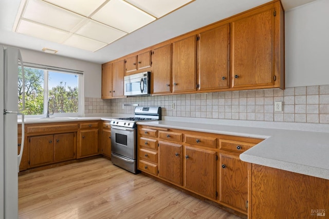 kitchen featuring brown cabinetry, light wood-style flooring, and stainless steel appliances