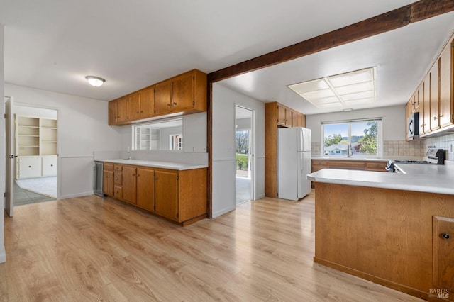 kitchen with brown cabinets, light wood-style floors, light countertops, and appliances with stainless steel finishes