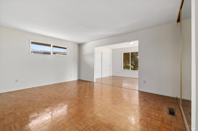 spare room featuring visible vents, a wealth of natural light, and baseboards
