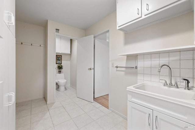 interior space featuring toilet, tasteful backsplash, vanity, and baseboards