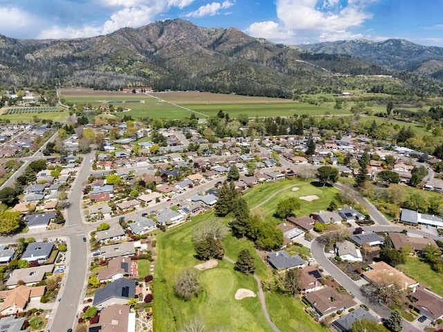 drone / aerial view featuring a mountain view, view of golf course, and a residential view
