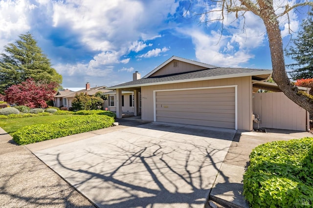 ranch-style home featuring a chimney, an attached garage, driveway, and roof with shingles