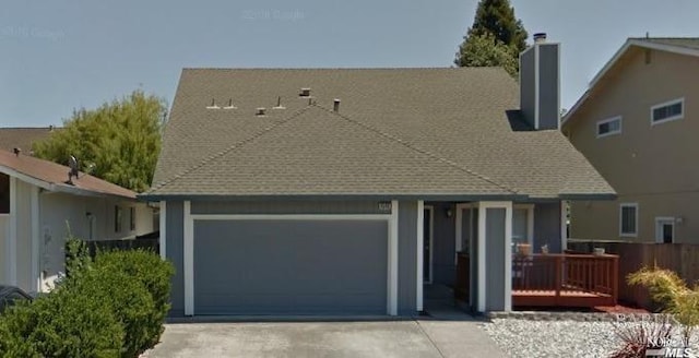 view of front of property with a garage, concrete driveway, and roof with shingles