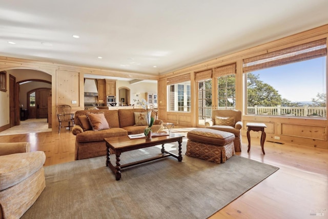 living room featuring plenty of natural light, arched walkways, recessed lighting, and light wood-style floors