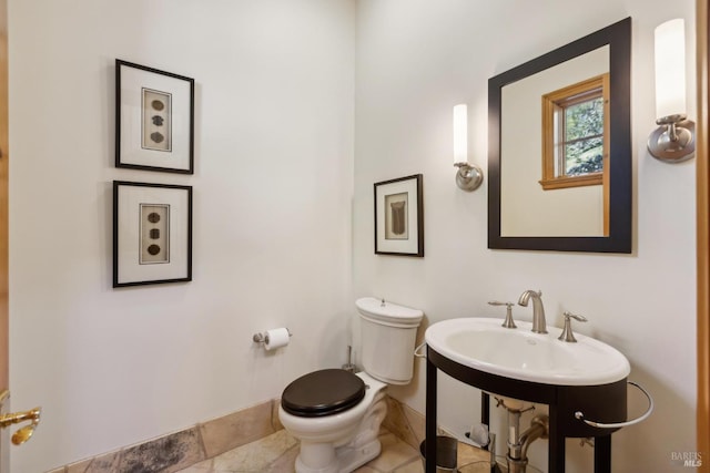 half bathroom featuring baseboards and toilet