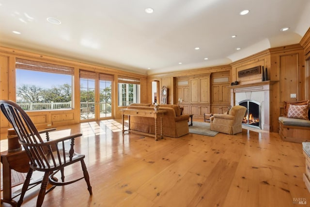 living area with light wood finished floors, a warm lit fireplace, and recessed lighting