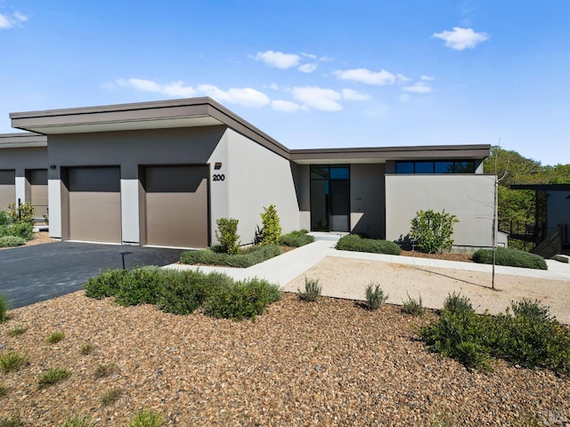 view of front of home with aphalt driveway, stucco siding, and an attached garage