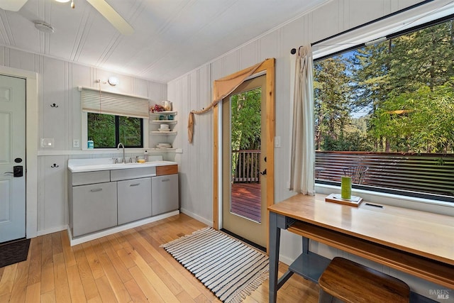 kitchen with light countertops, a sink, gray cabinetry, light wood-style flooring, and ceiling fan