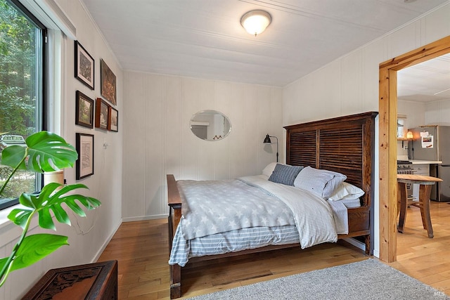 bedroom with hardwood / wood-style flooring and freestanding refrigerator