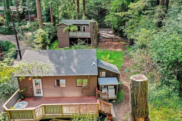 rear view of property with a wooden deck and roof with shingles