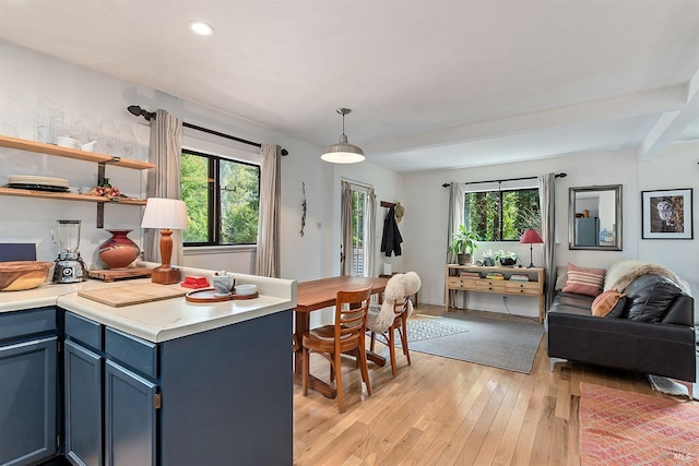 kitchen with light countertops, hanging light fixtures, open floor plan, light wood-style floors, and blue cabinetry