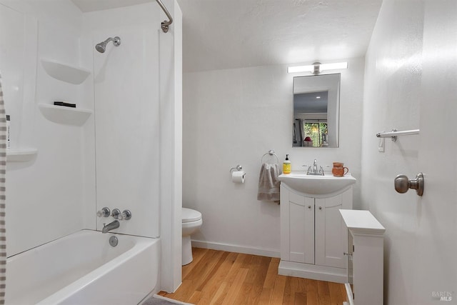 bathroom with vanity, toilet, baseboards, shower / tub combination, and wood finished floors
