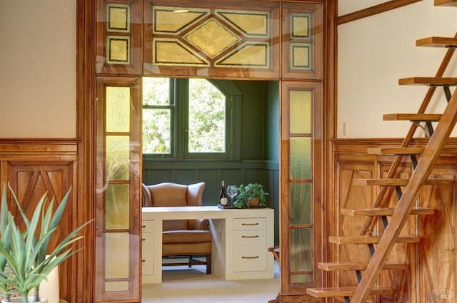 doorway to outside featuring carpet floors, a decorative wall, and a wainscoted wall