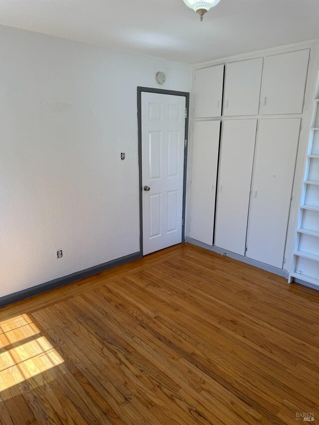 unfurnished bedroom with a closet, baseboards, and wood finished floors