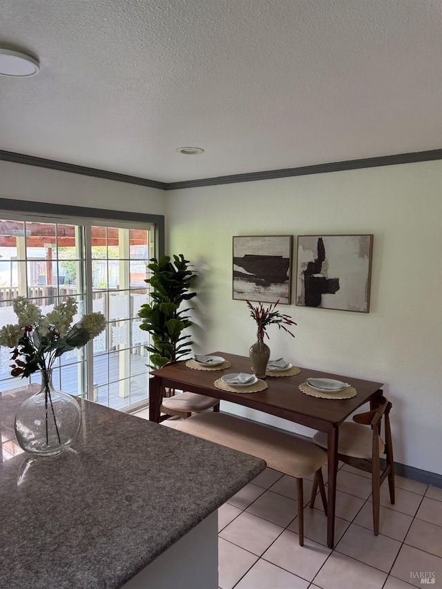 dining area featuring baseboards, a textured ceiling, crown molding, and light tile patterned floors